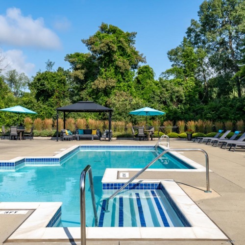 Relax and unwind poolside a pool with chairs and umbrellas by it